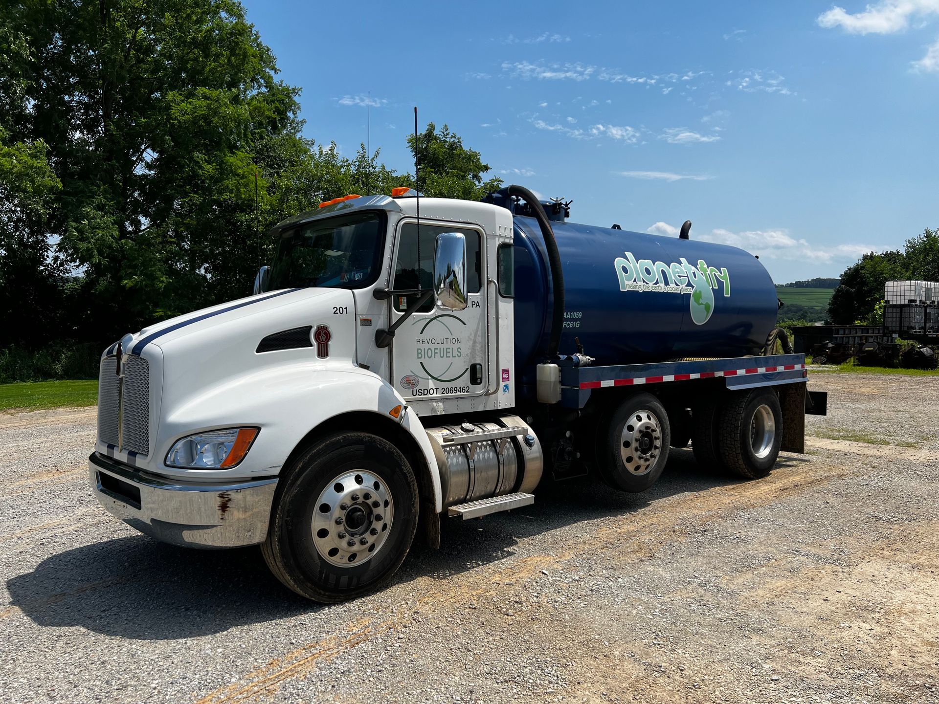 A white and blue truck is parked in a gravel lot.