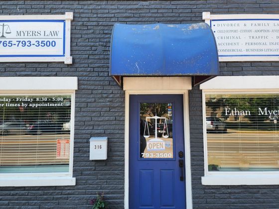 Blue awning and door on a dark brick storefront with law office