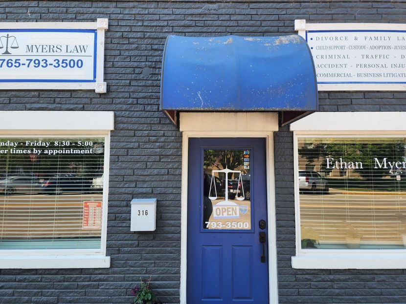 Blue storefront door and windows with signs for a law office on a brick building
