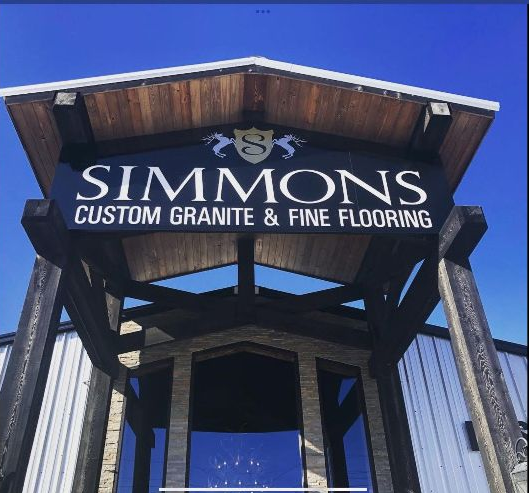 SIMMONS Custom Granite & Fine Flooring sign on a building entrance against a blue sky