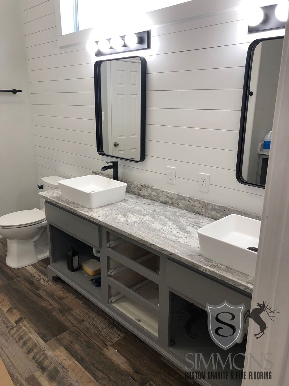 Modern bathroom with double vanity, white sinks, mirrors, and gray countertop
