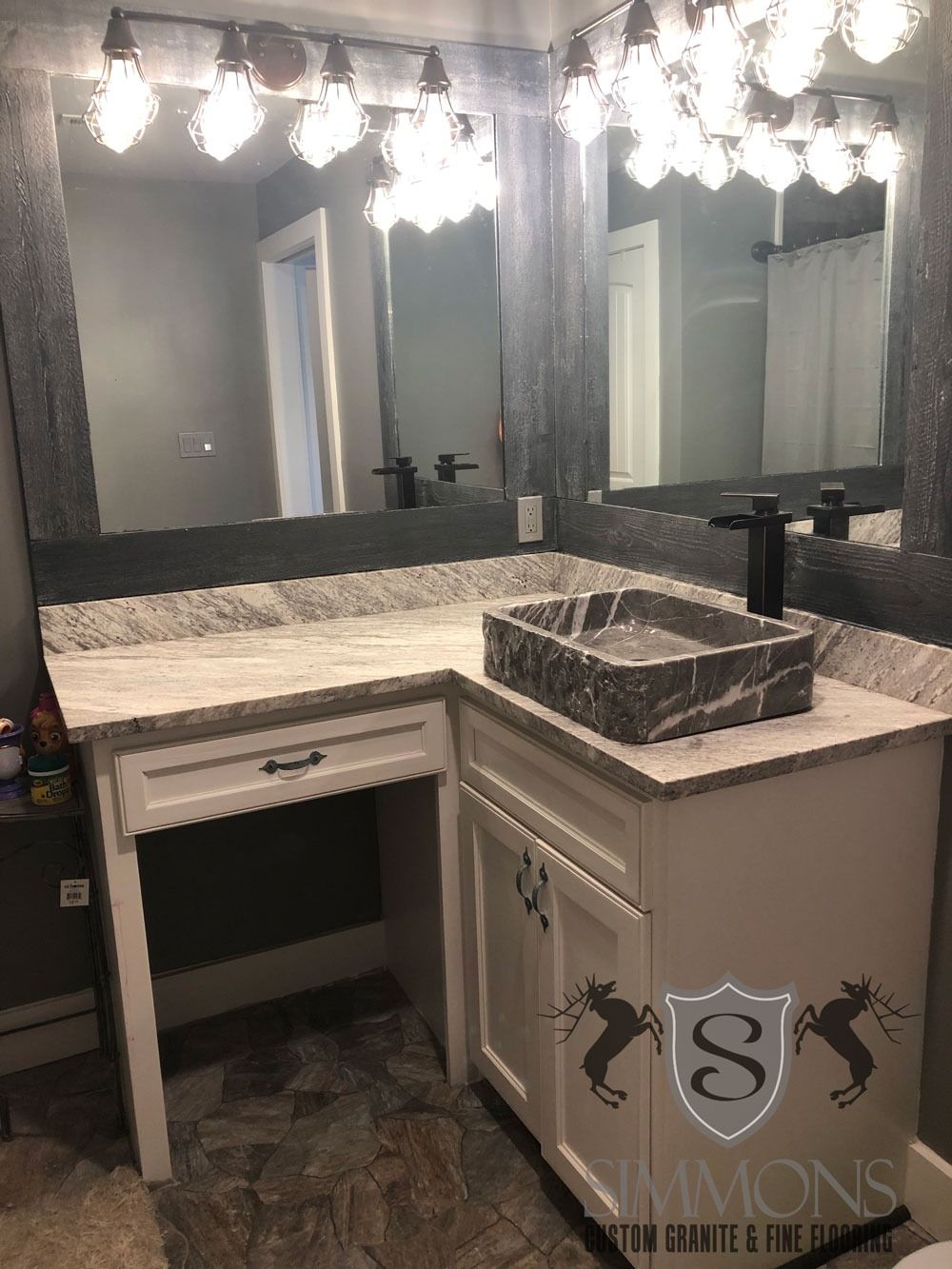 Modern bathroom vanity with large mirror, bright lights, dark countertop, and square vessel sink