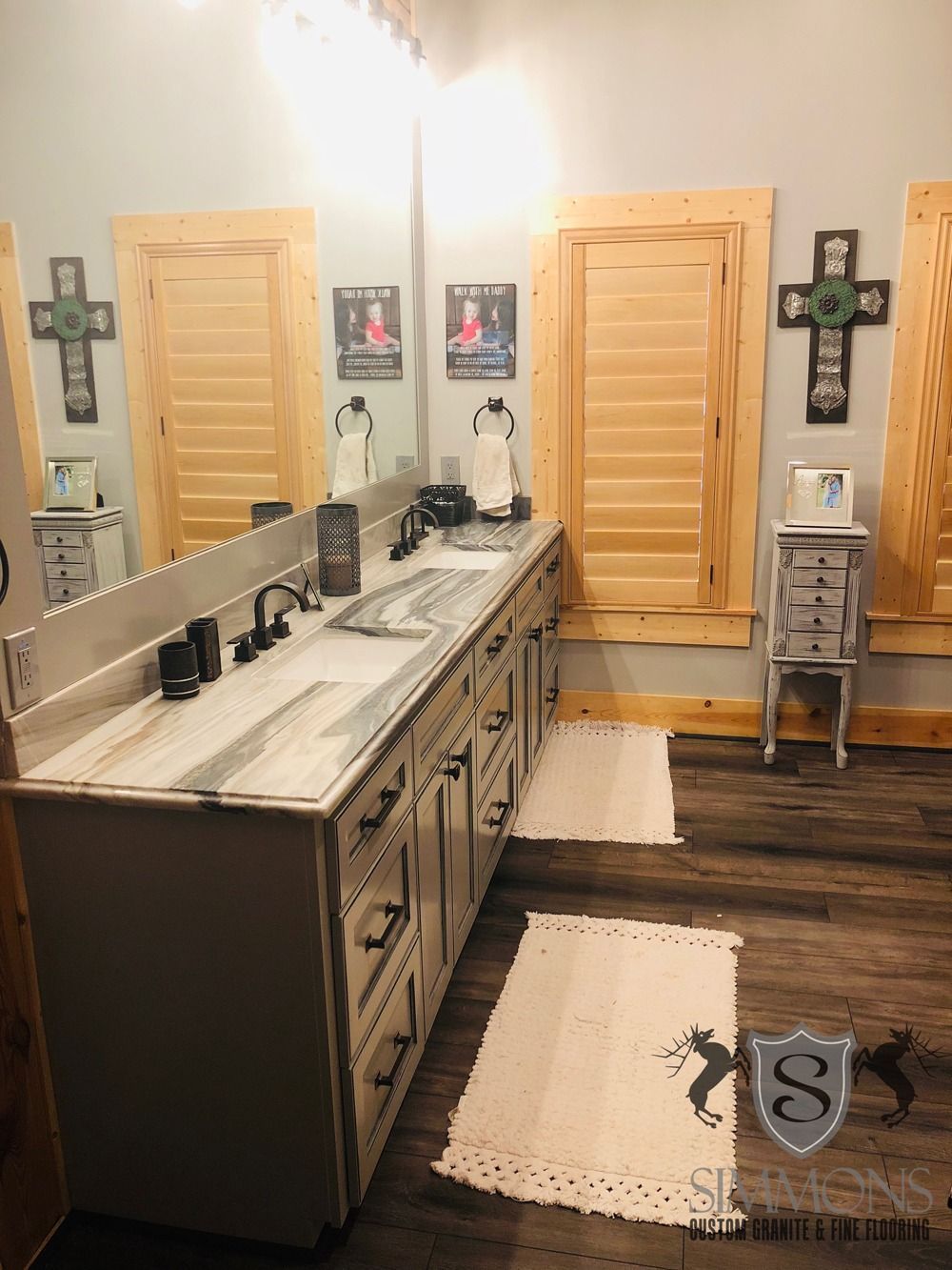 Spacious bathroom with dual vanities, large mirrors, wooden doors, and dark wood flooring.
