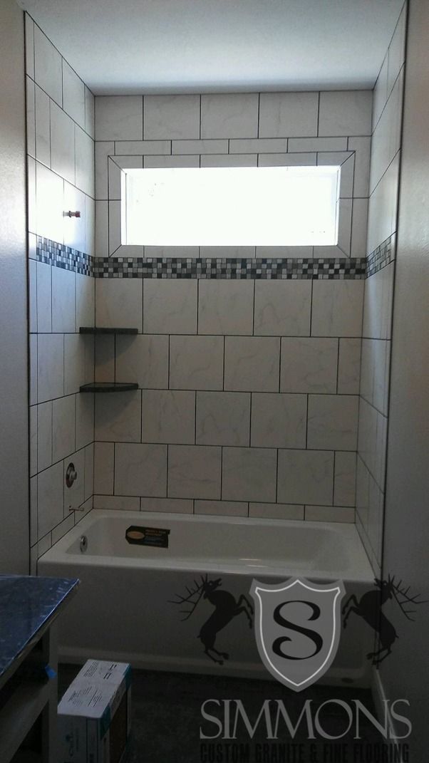 Small white-tiled bathroom with a bathtub, high window, and partial shower shelving.