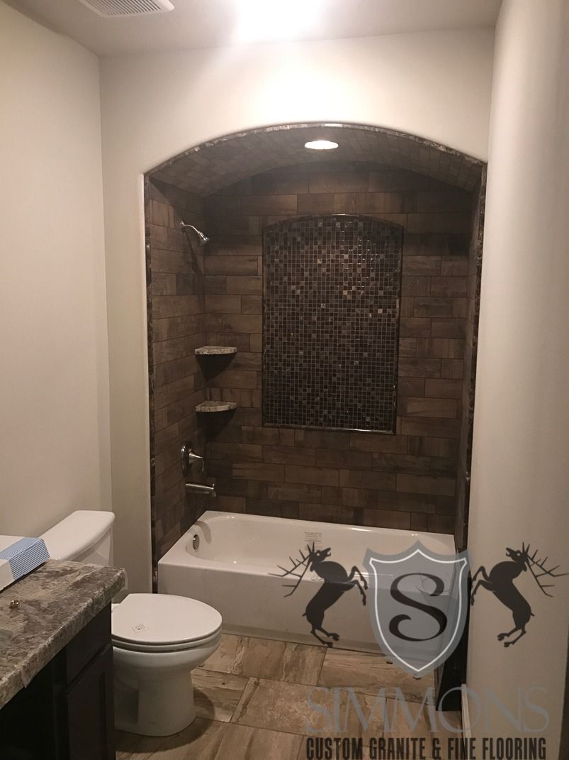 Small bathroom with toilet, vanity sink, and brick-tiled shower nook with dark window screen.