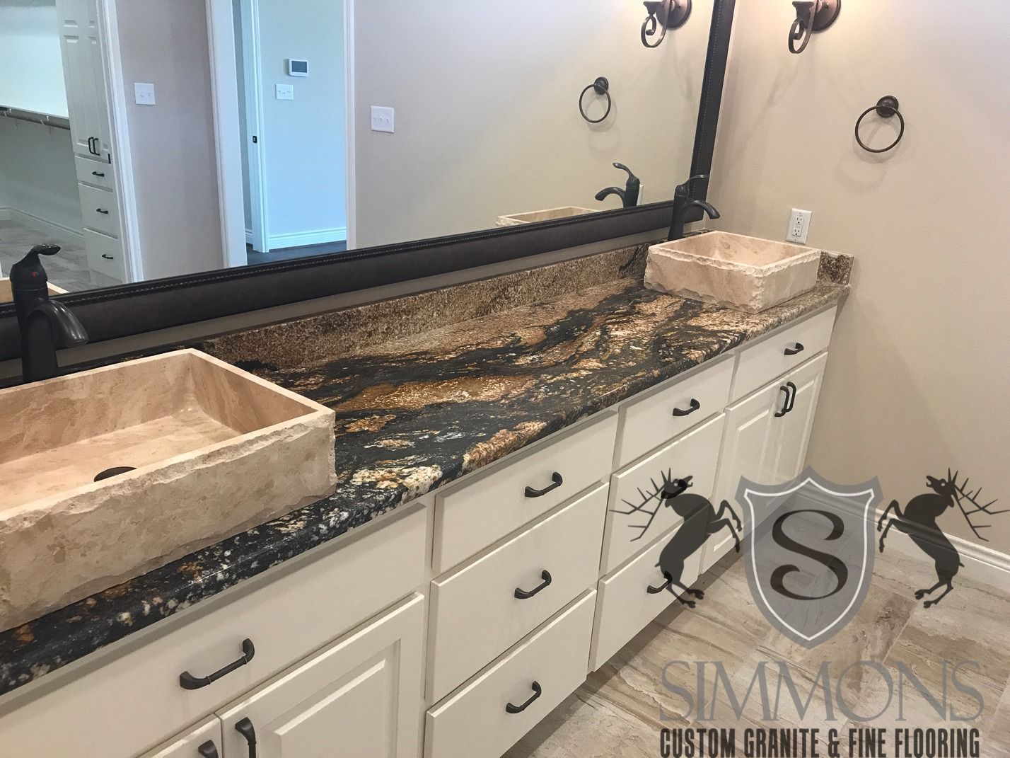 Bathroom vanity with dark granite countertop, white cabinets, and a sink under a large mirror.