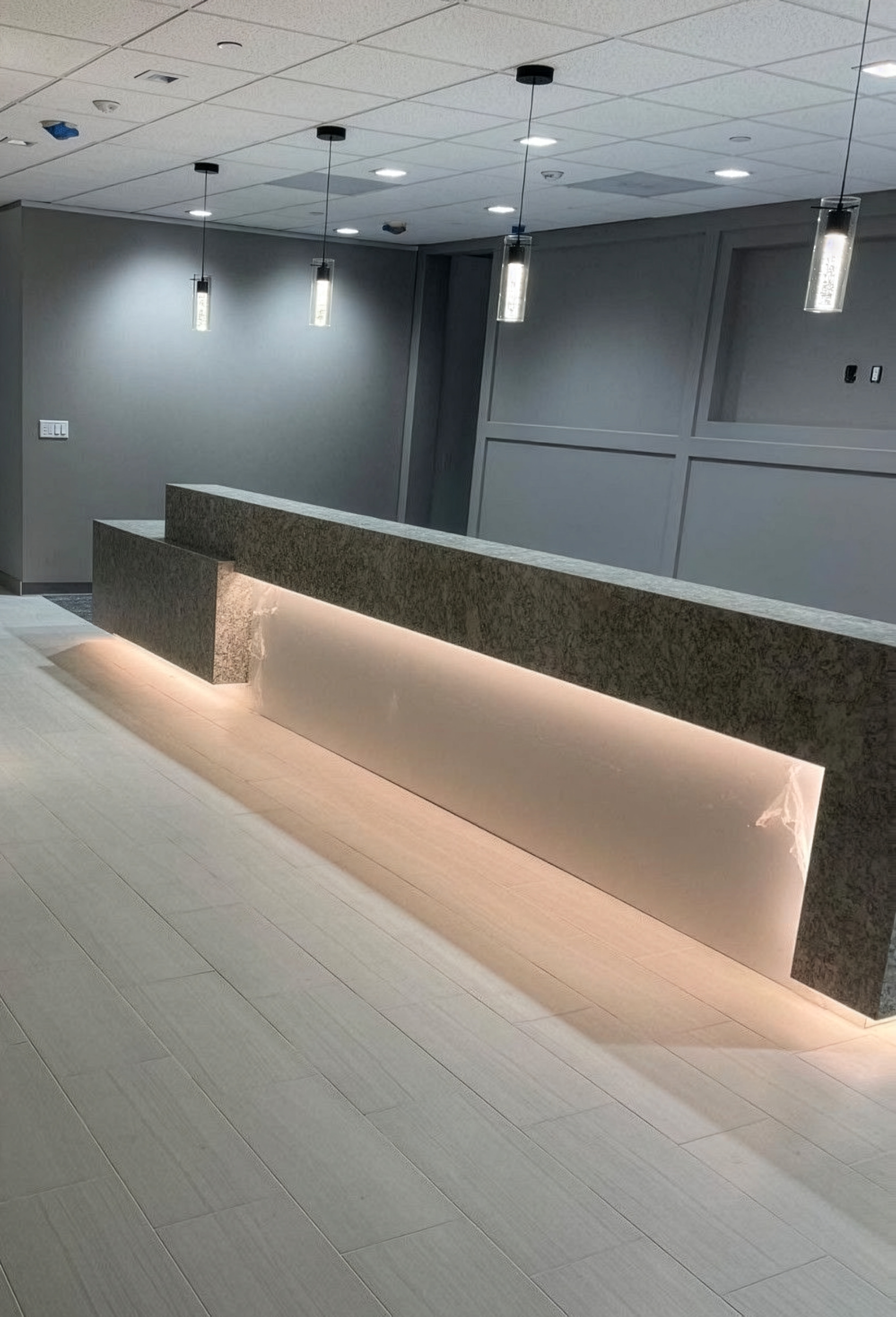 Modern commercial countertop with a long illuminated stone and gray walls on a tiled floor