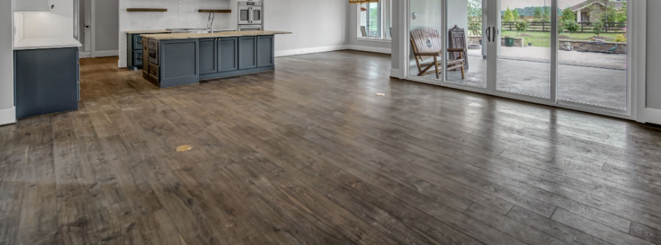 Empty modern kitchen and living area with wide-plank wood floors and large sliding glass doors