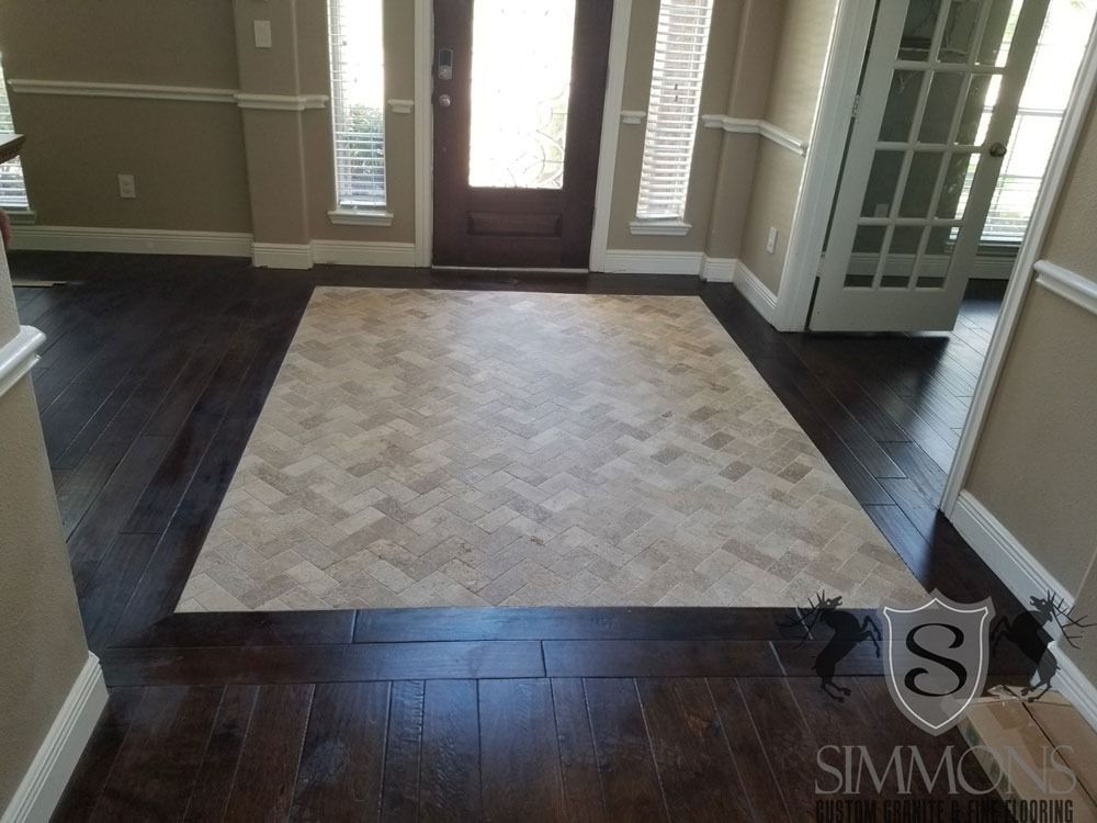 Empty foyer with dark hardwood floors and a light patterned inlay near the front door