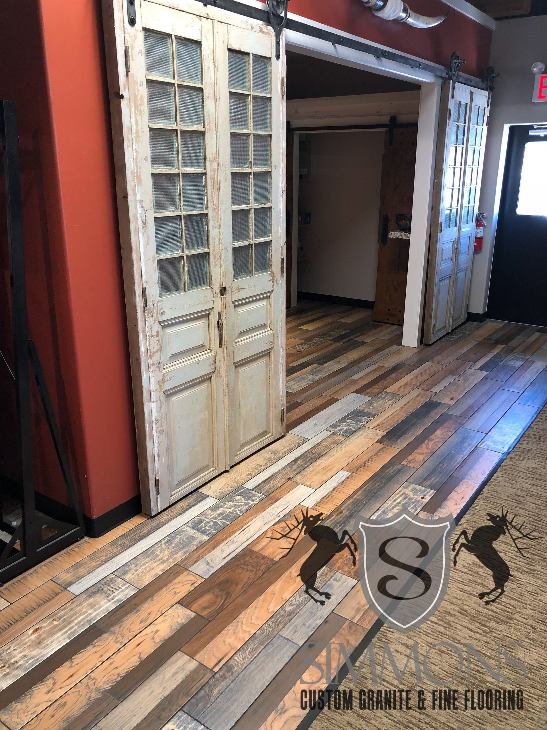 Old wooden hallway with open double doors, worn floorboards, and red-and-white walls.