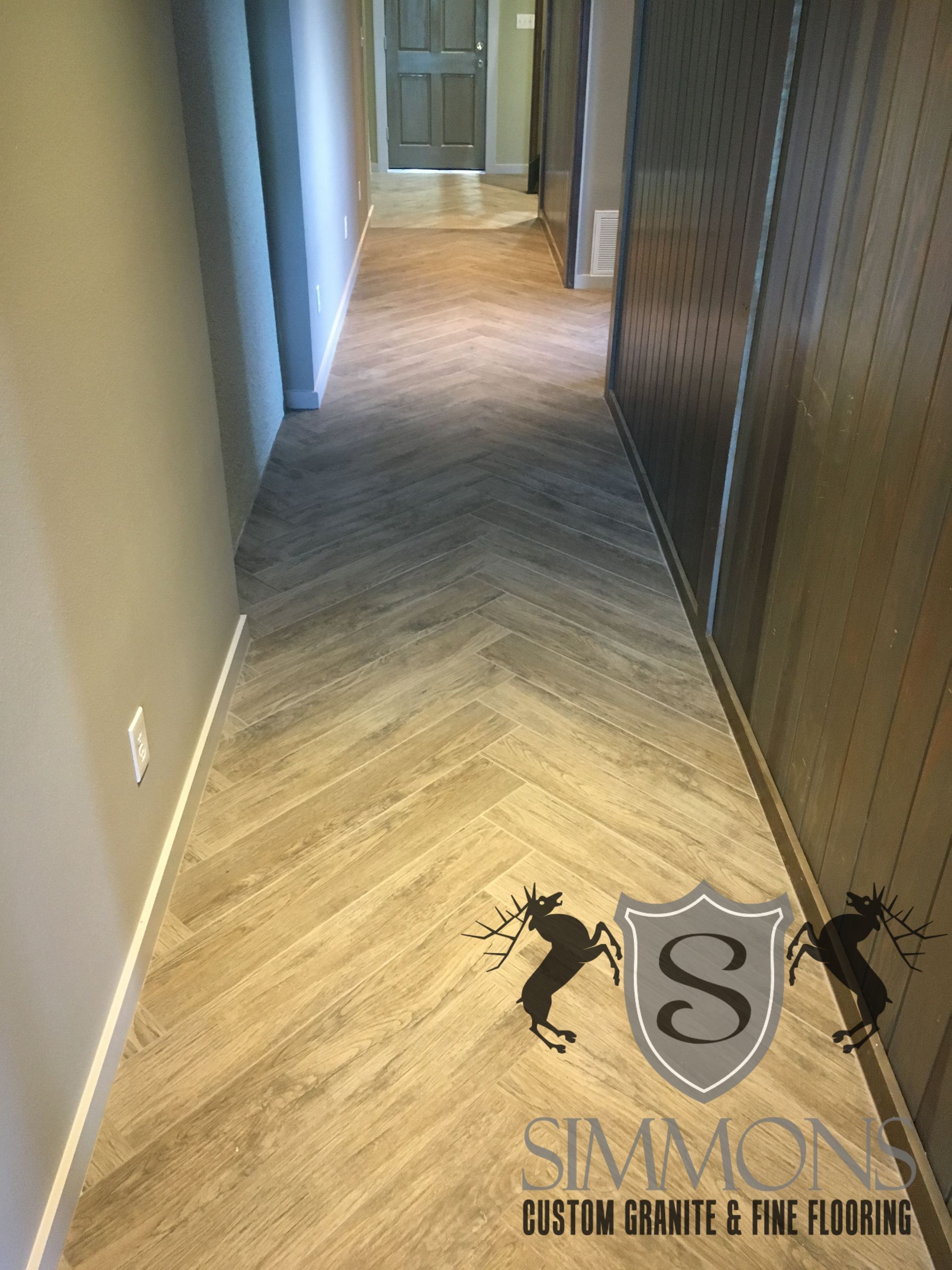 Empty hallway with beige walls, wood-pattern floor, and doors along the sides.