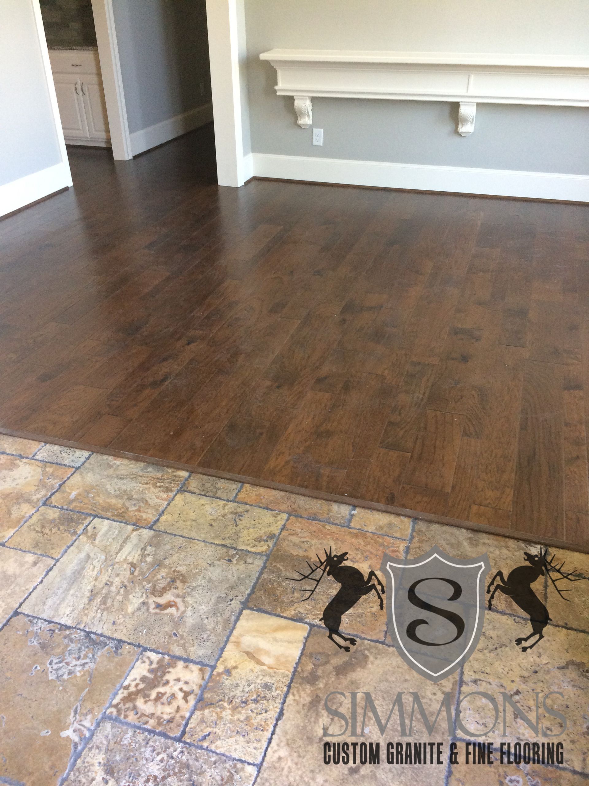 Empty room with brown hardwood floors, tiled entryway, and white built-in bench on gray walls.