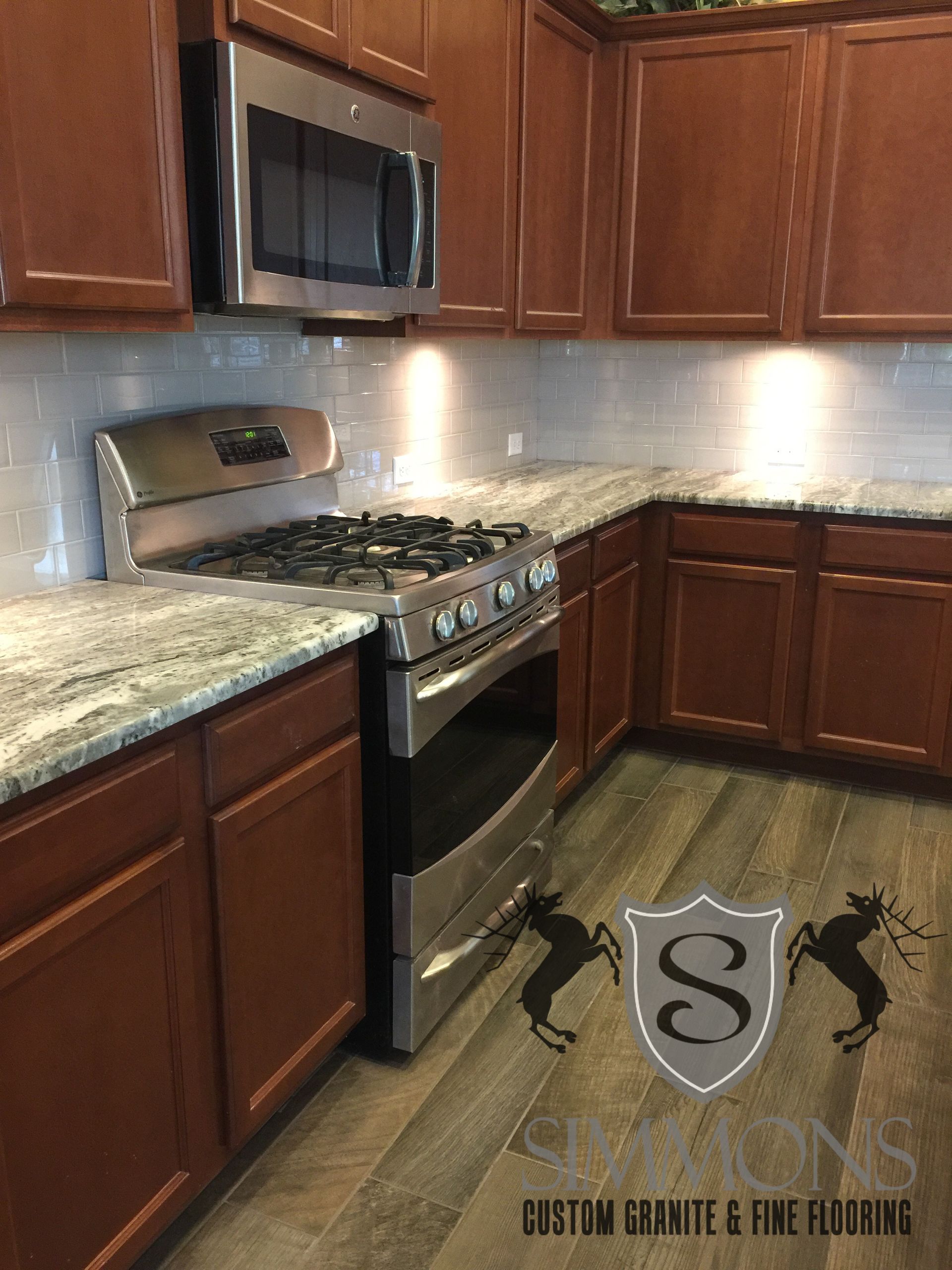 Modern kitchen with dark wood cabinets, stainless steel stove and microwave, and granite countertops.