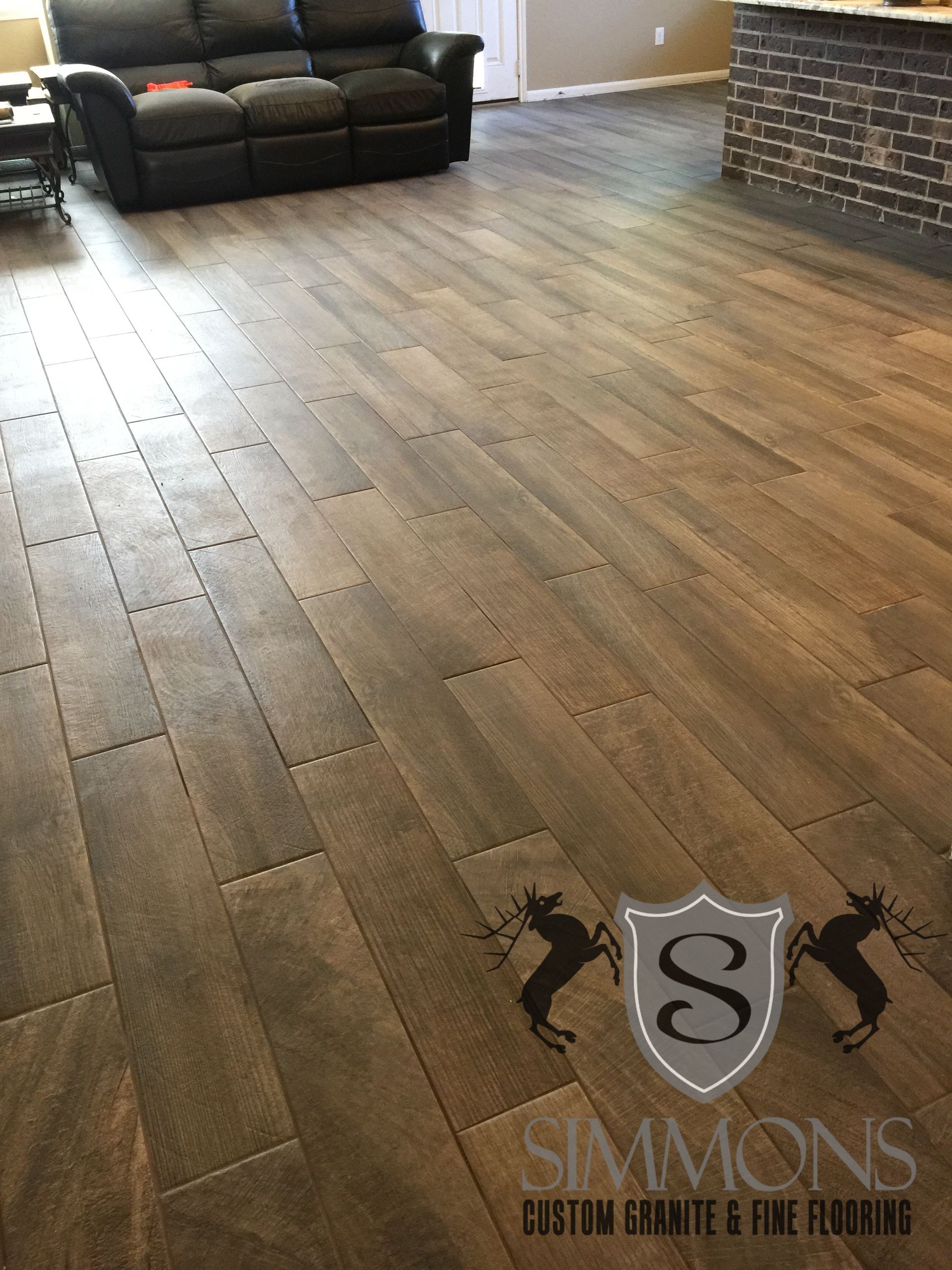 Empty room with wide gray wood floor and a sofa along the back wall