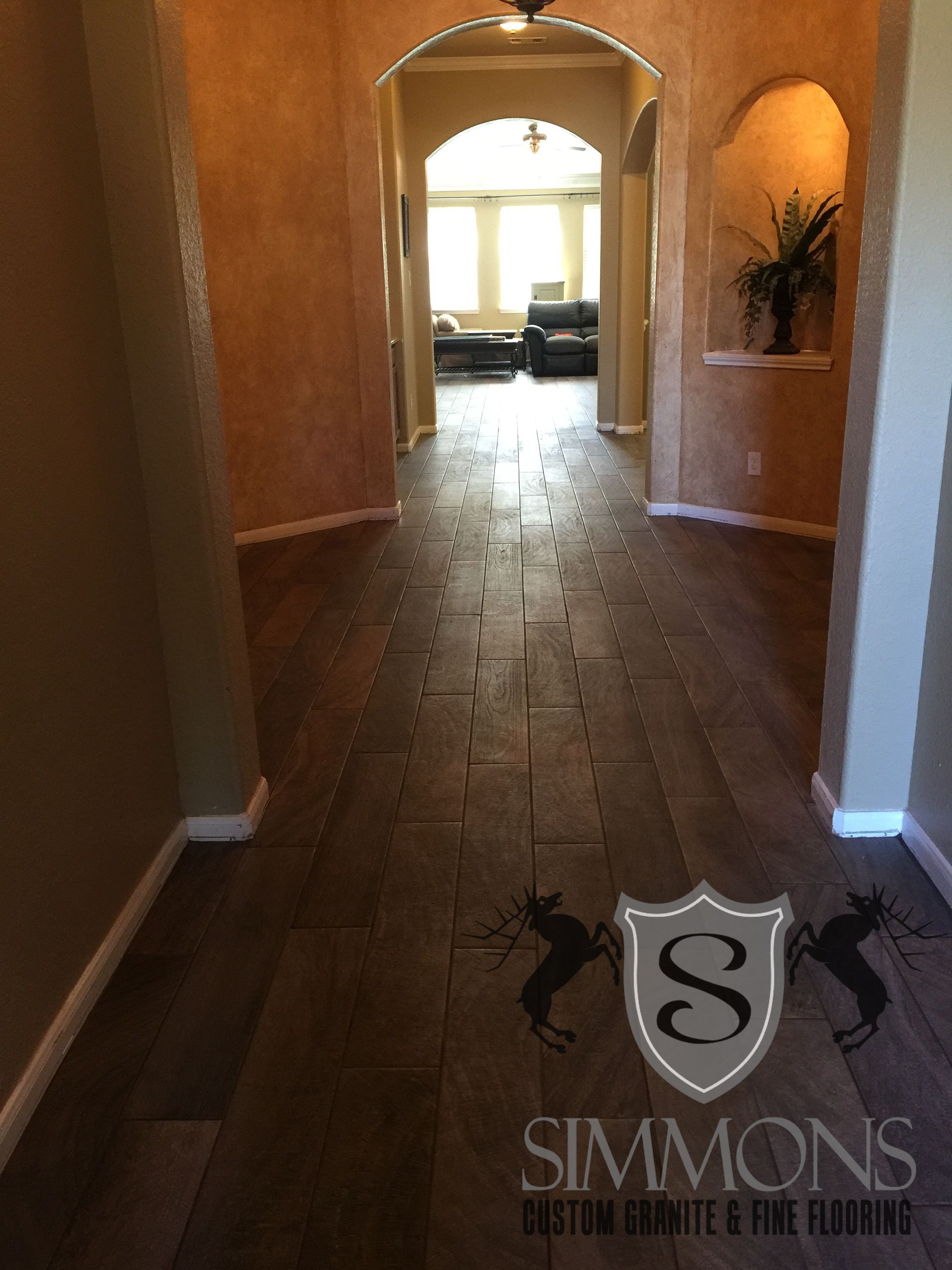 Dim hallway with wood floors leading to a bright arched living room and couch.
