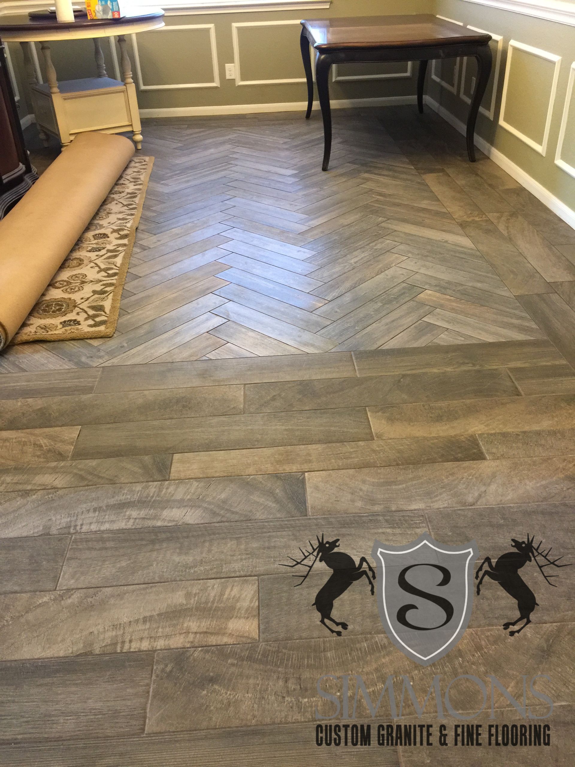 Dark herringbone wood floor installation in a room with white wainscoting and a small table.