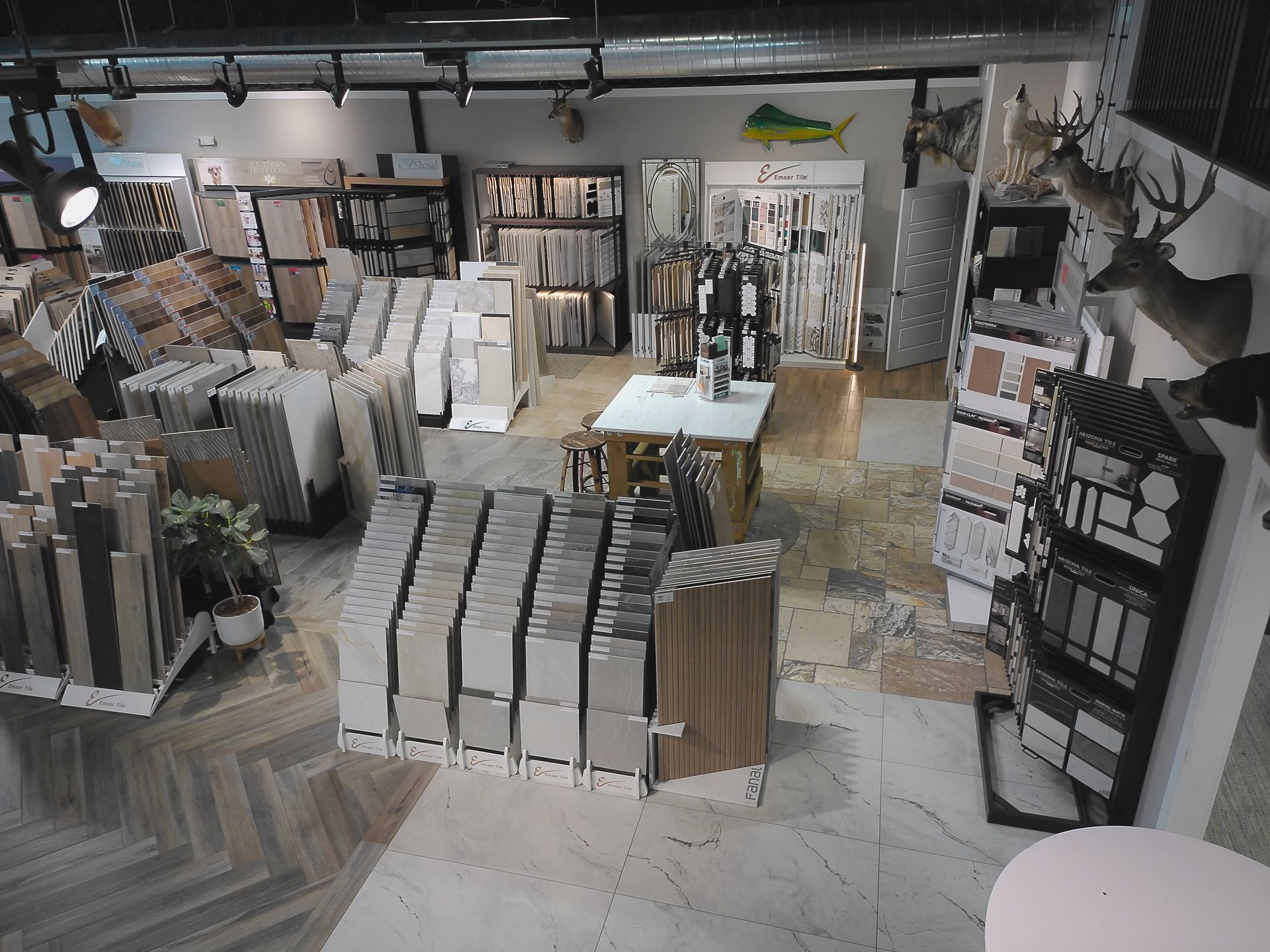 Indoor retail store with stacks of gray tiles, display shelves, and countertops under bright lights