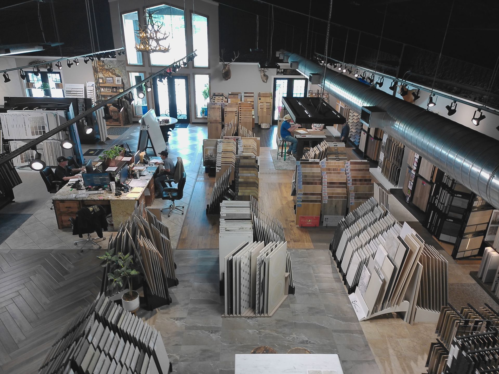 Wide-angle view of a home improvement store aisle with stacked flooring, tiles, and lumber displays