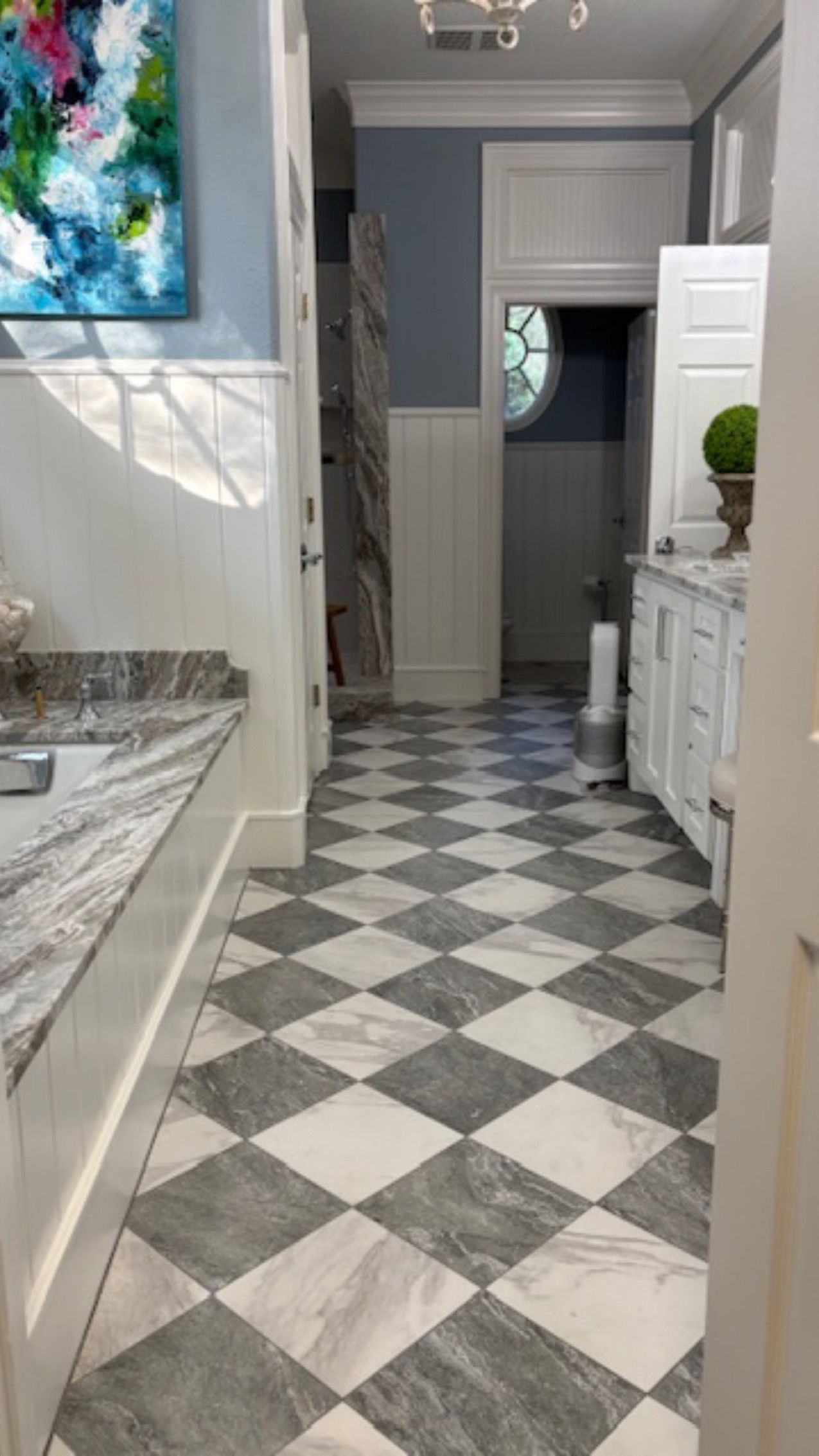 Narrow hallway with black-and-white checkered floor leading to a bathroom or bedroom, white walls and cabinets.