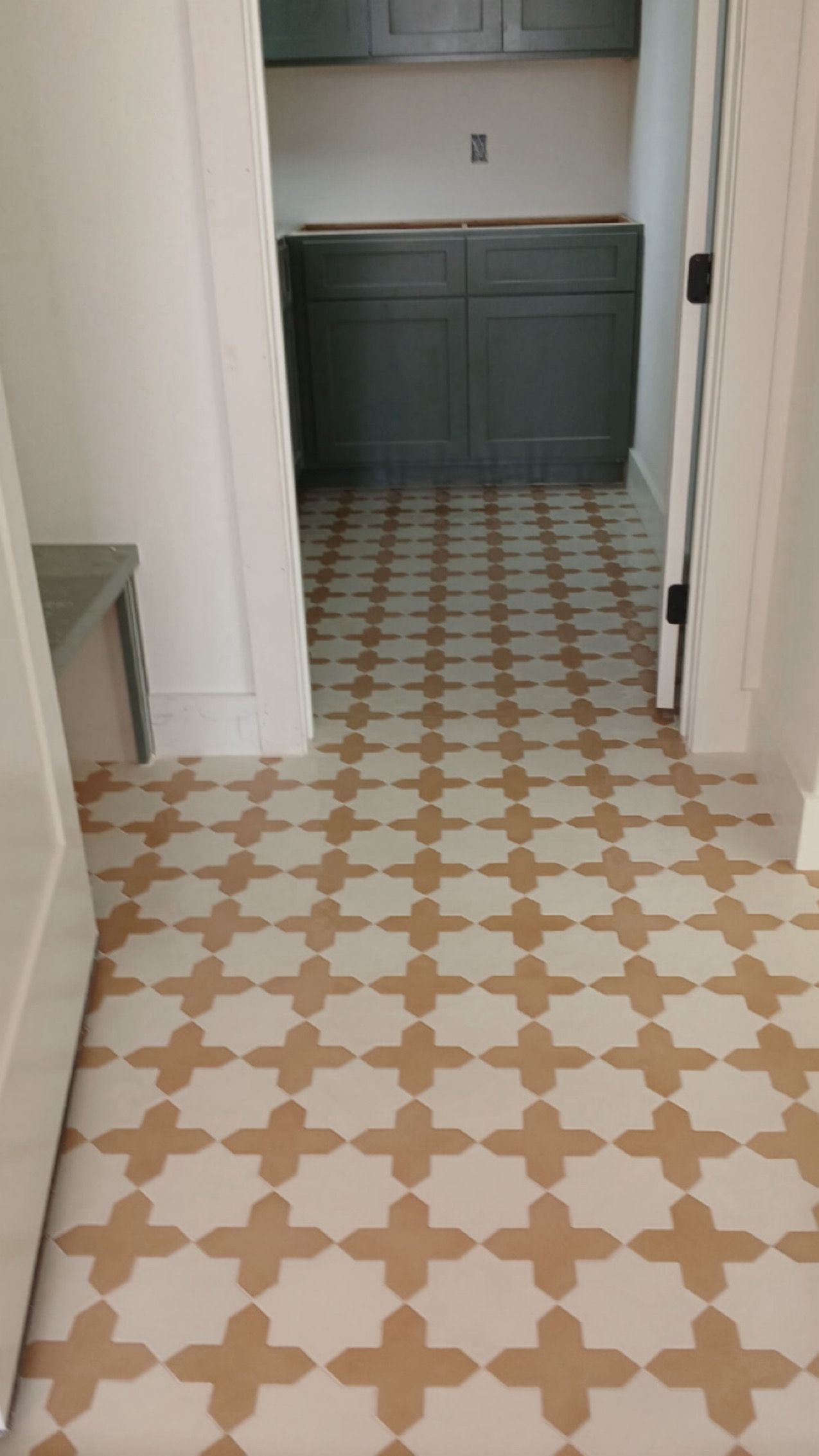 Narrow hallway with patterned tile floor leading to a teal bathroom vanity.