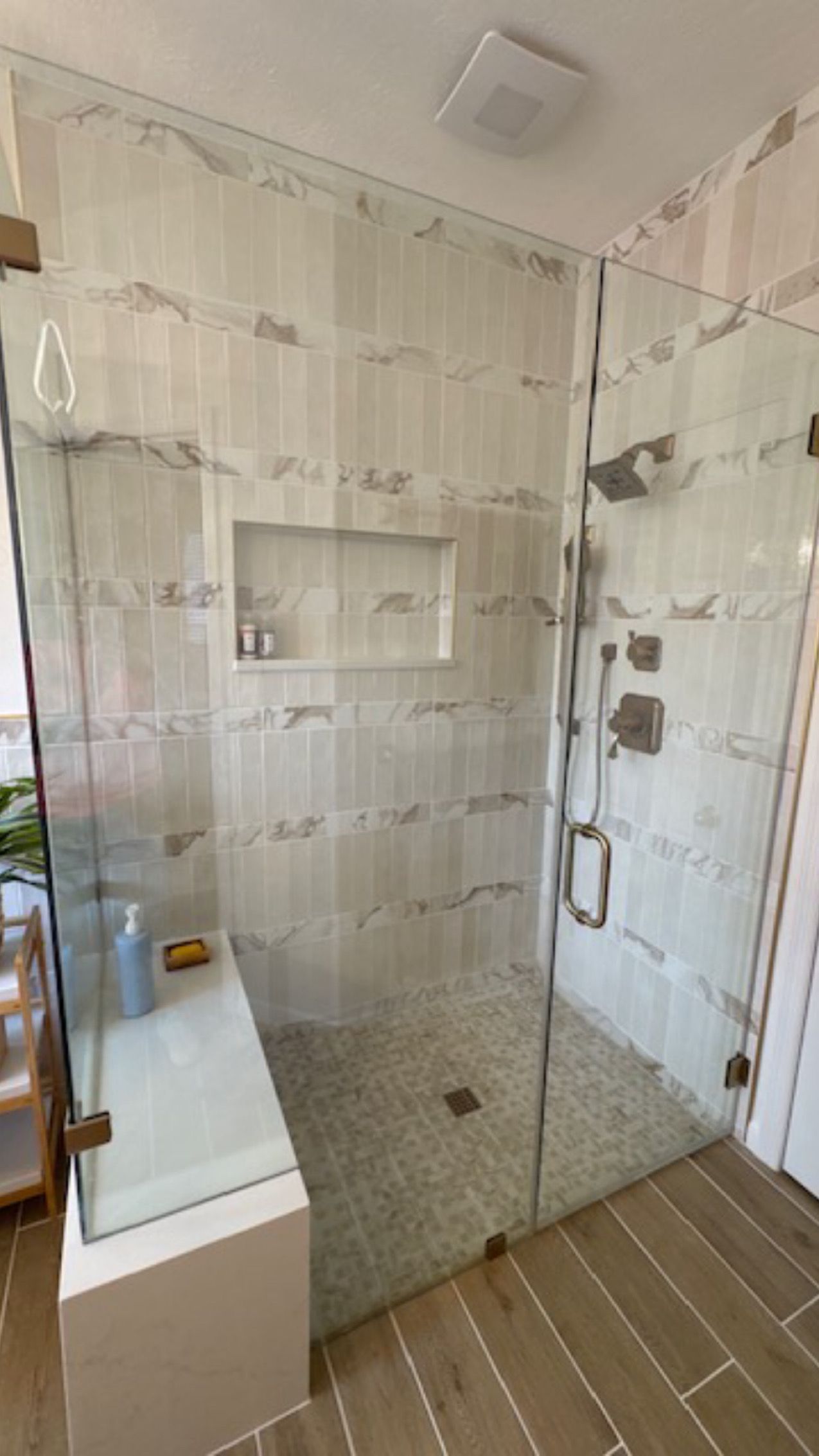 Modern bathroom with glass-enclosed shower, white vanity, and wood-look tile floor
