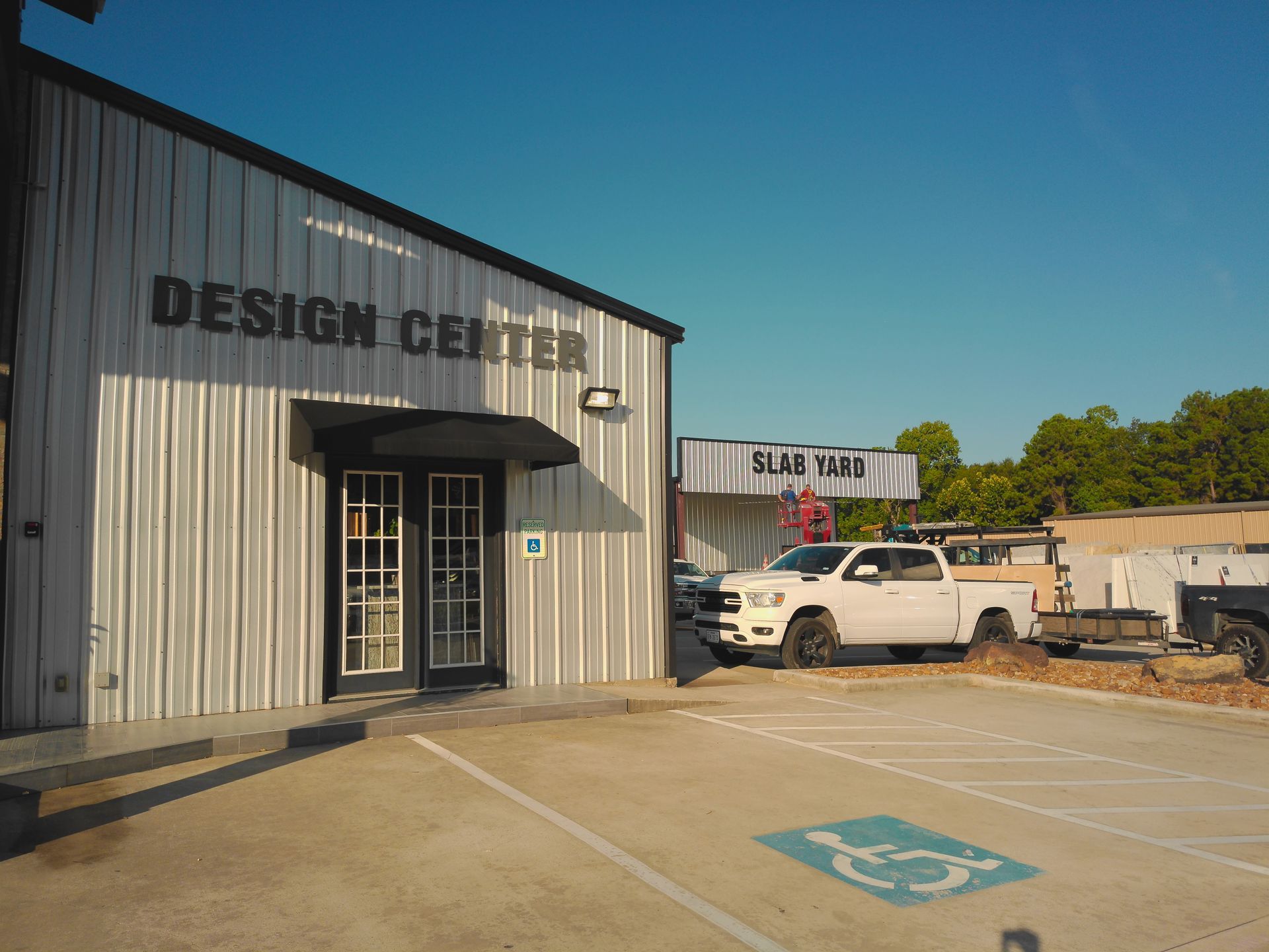 Exterior of a Design Center with parking lot and a white pickup truck under a clear blue sky