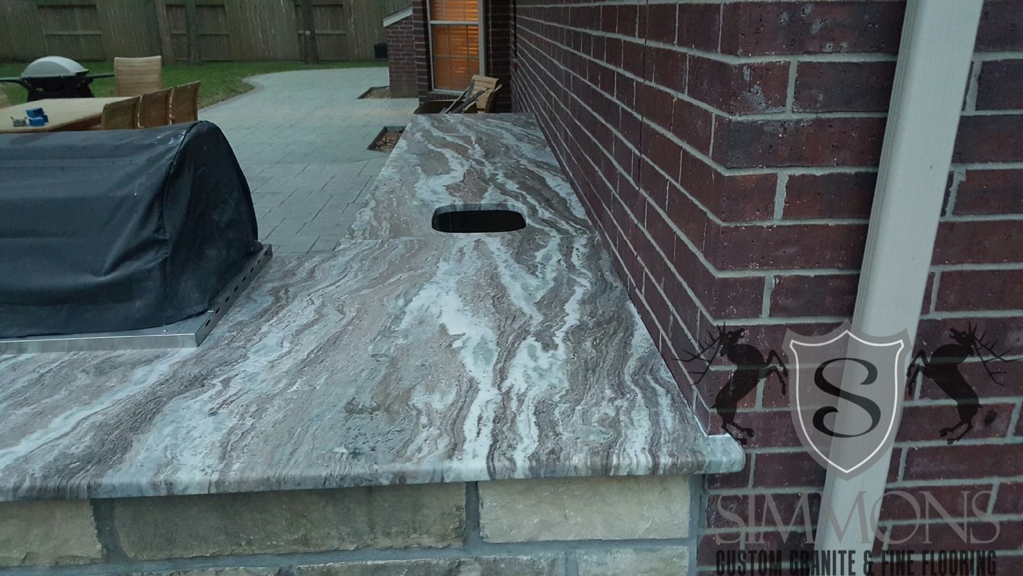 Wooden deck beside a brick wall with snow or frost on the surface and a small black object near the center.