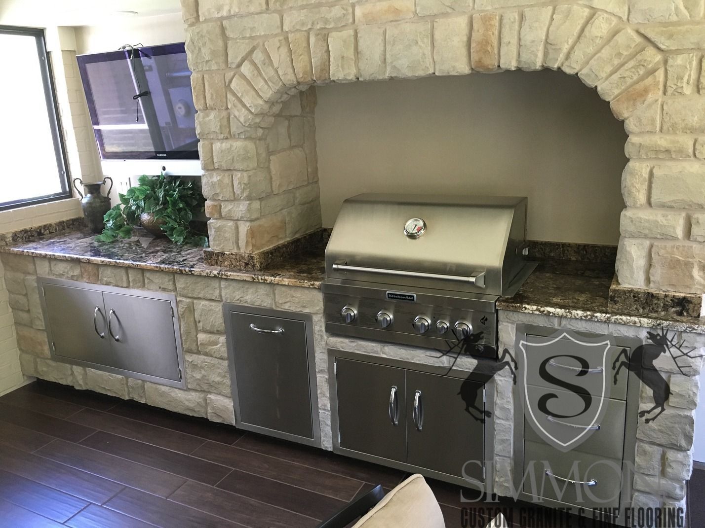 Outdoor stone barbecue area with built-in grill, sink, and granite countertop