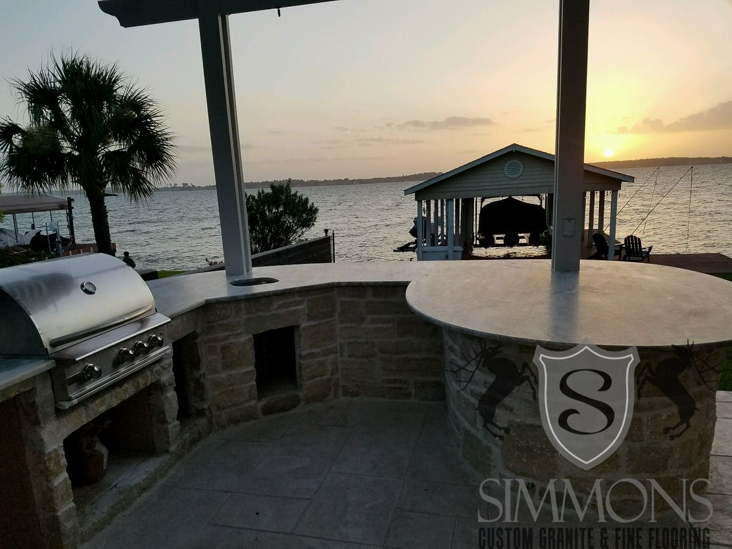 Beachfront patio with grill and stone bar overlooking the ocean at sunset