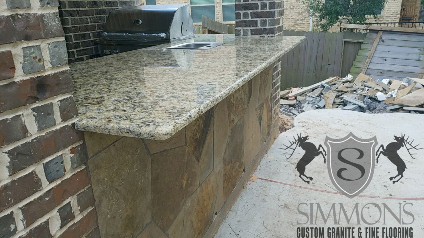 Outdoor stone patio with granite counter and brick walls, with debris and a 