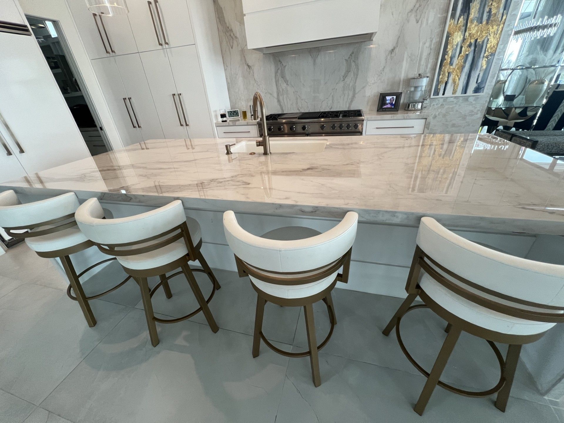 Modern kitchen with a large marble island counter and four curved chairs