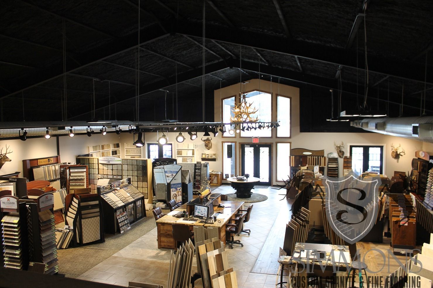 Wide-angle view of a furniture showroom with sofas, tables, and decor under a dark ceiling