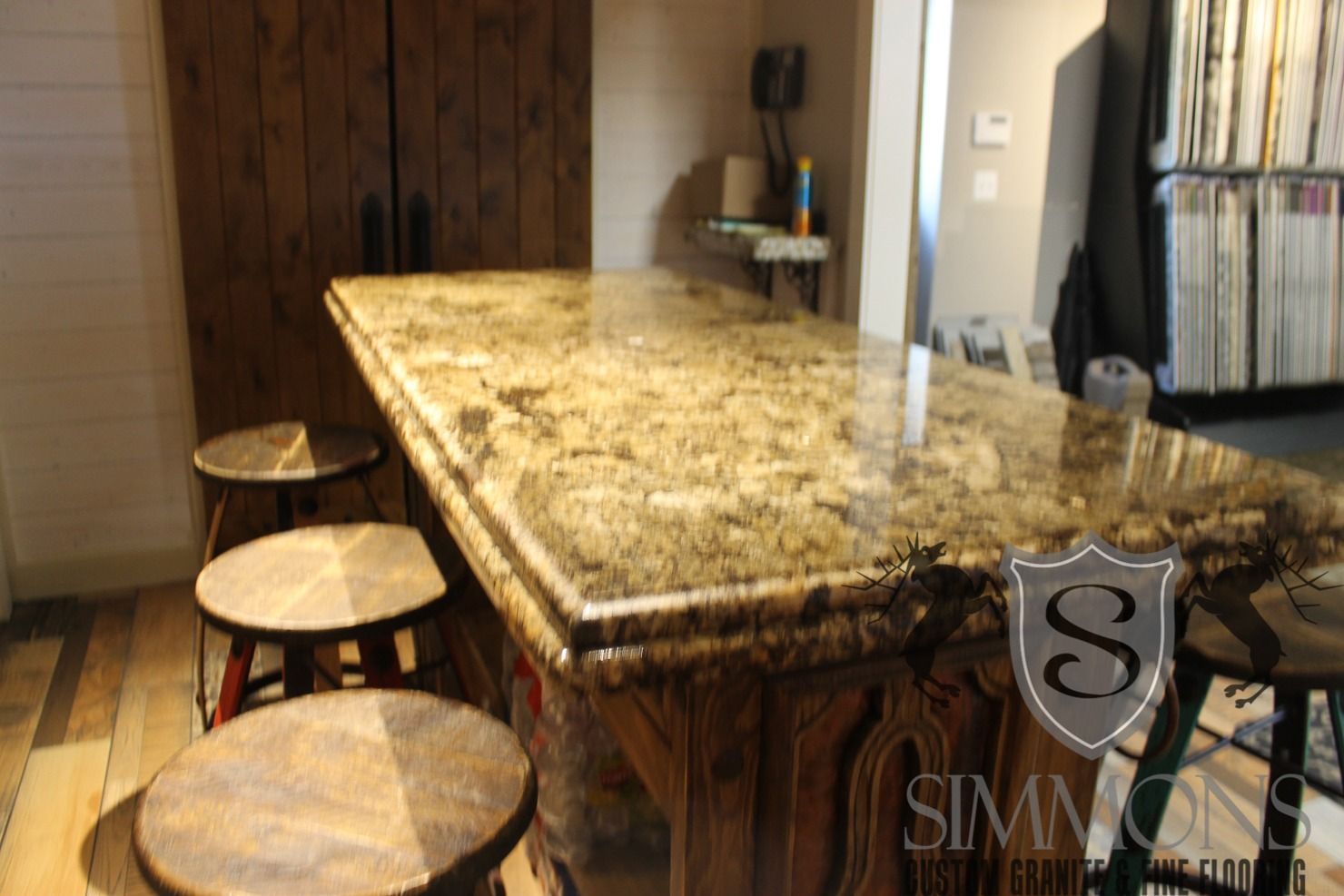 Granite kitchen island with three round stools in a bright home interior