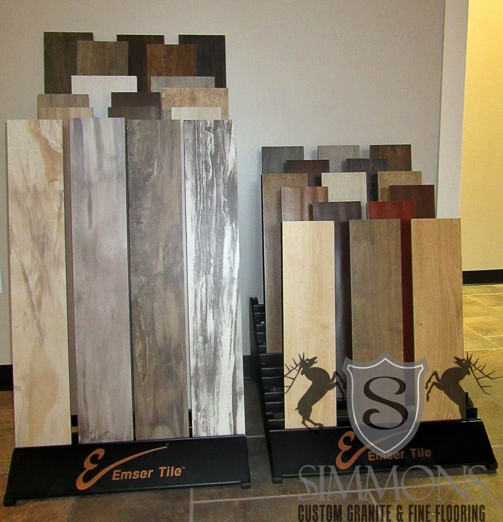 Display of large and small sample tiles in wood and stone finishes on black stands