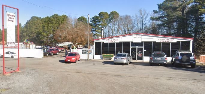 Building with sign, cars parked out front. Red sign on the left side reads 