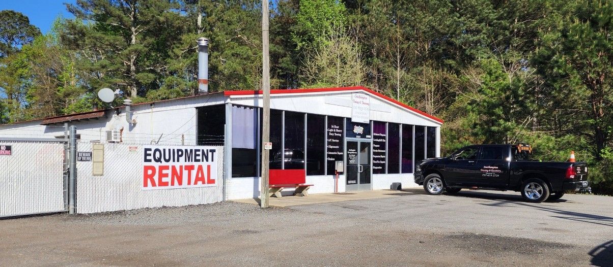 Small white equipment rental building with red trim and a black pickup truck parked outside
