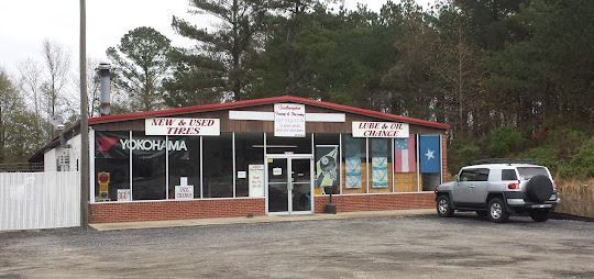 A tire shop with a red roof. A silver SUV is parked in front.