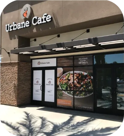 Exterior of Urbane Cafe storefront with glass doors and awning in a shopping center