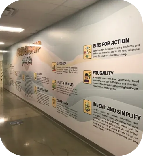 Hallway wall with large motivational posters and text, including “Bias for Action,” “Frugality,” and “Invent and Simplify”
