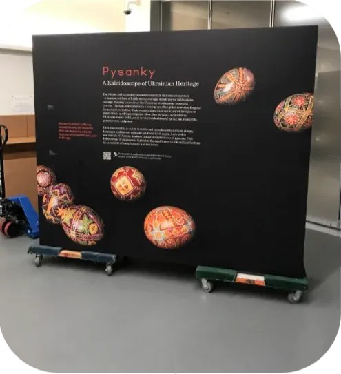 Black exhibition board on carts with “Psyche” title, text, and colorful planet-like images