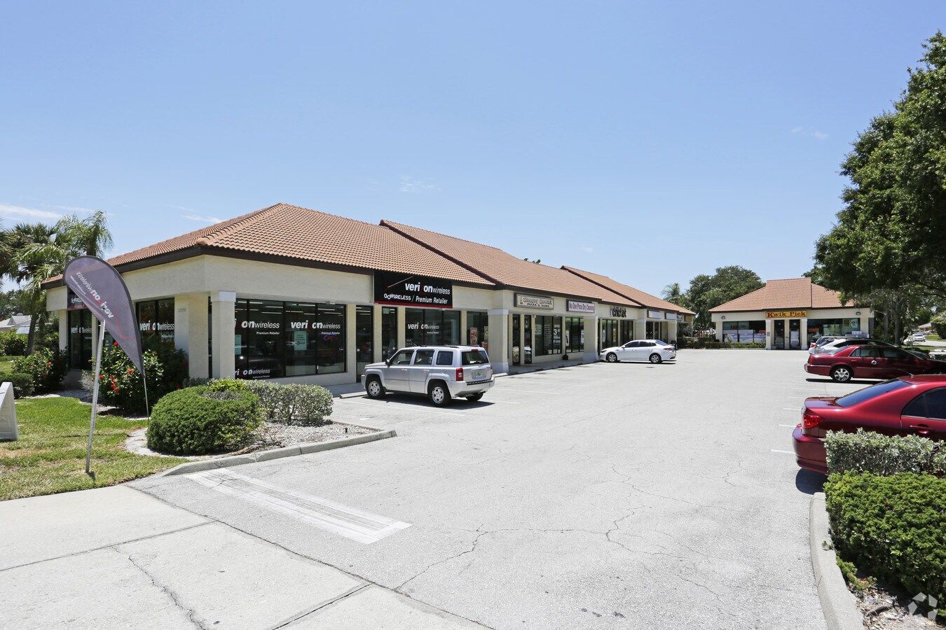 A one-story commercial building with multiple storefronts and cars parked in front.