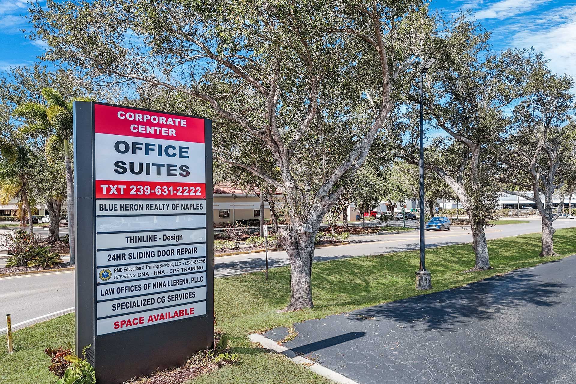 Sign for Corporate Center Office Suites along a road, with trees and blue sky.