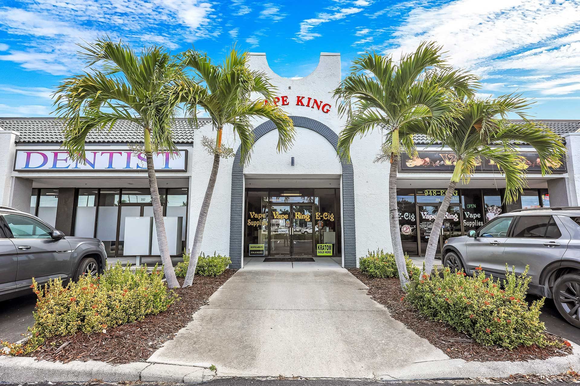 Exterior of a commercial building with palm trees in front; businesses include a dentist.