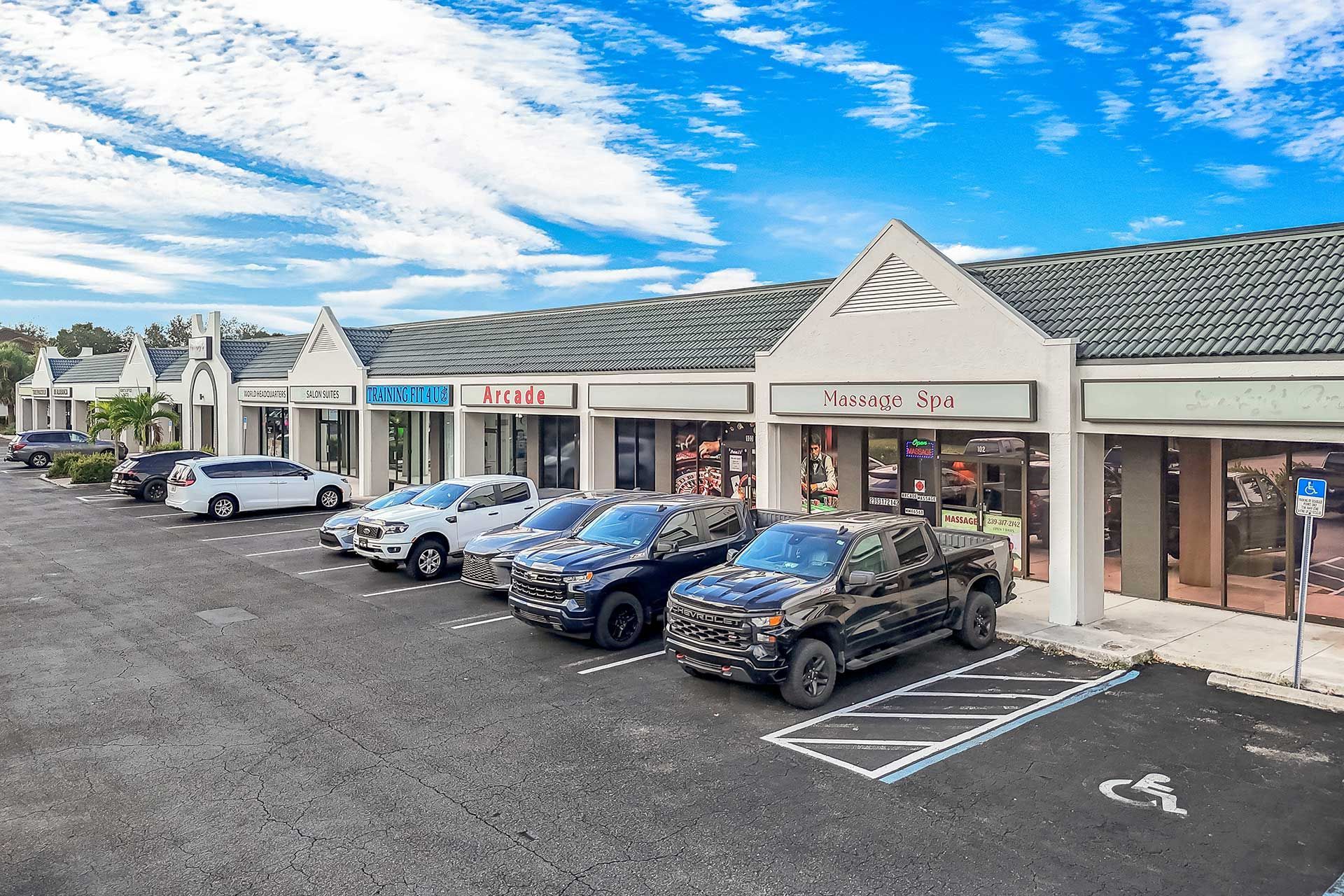 Strip mall with cars parked out front on a sunny day.