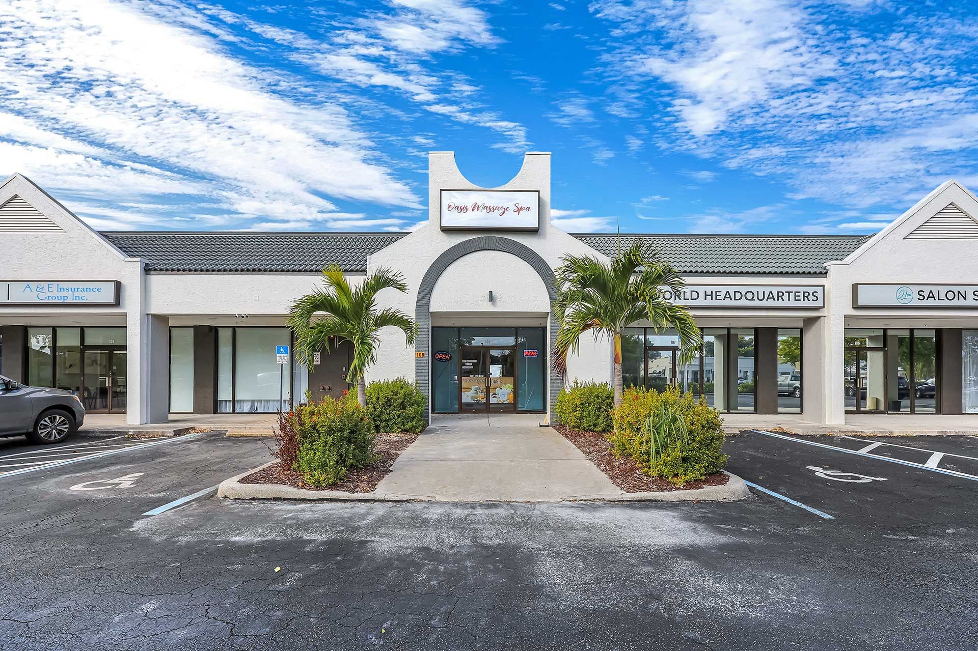 Exterior view of a shopping center with various storefronts under a blue sky.