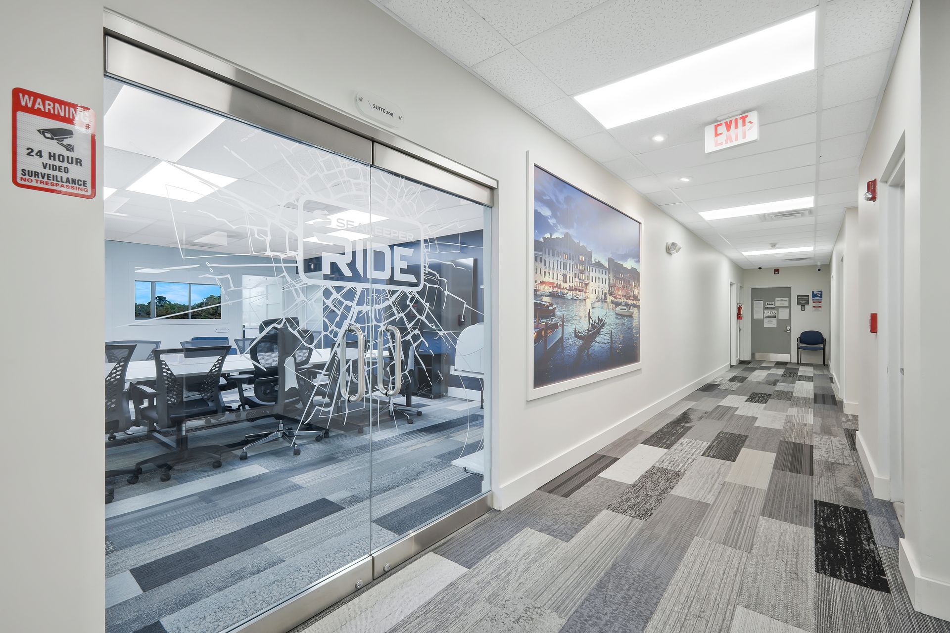 Hallway with office on the left, artwork on the wall, and gray patterned carpet.