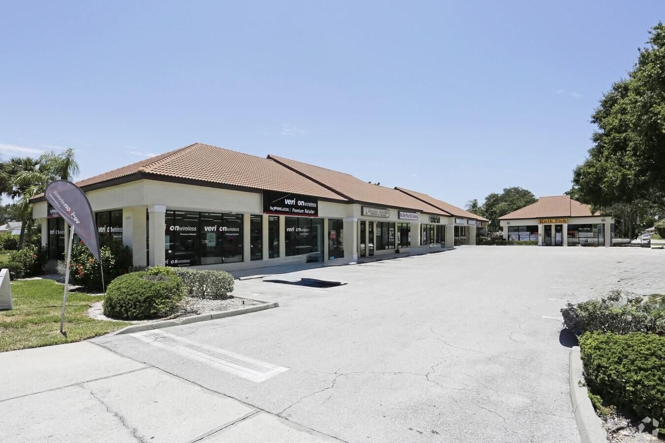 A row of retail storefronts with a terracotta tile roof, sunny day.
