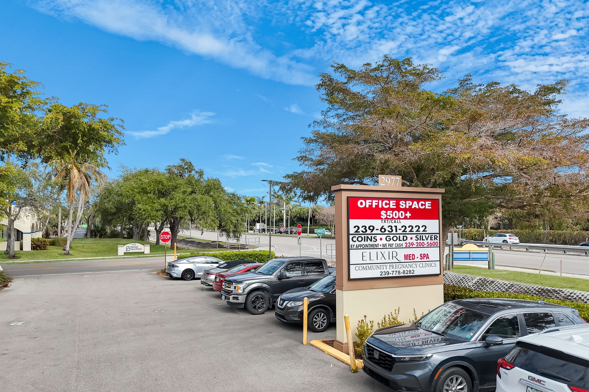 Parking lot with cars in front of an office building and a sign advertising