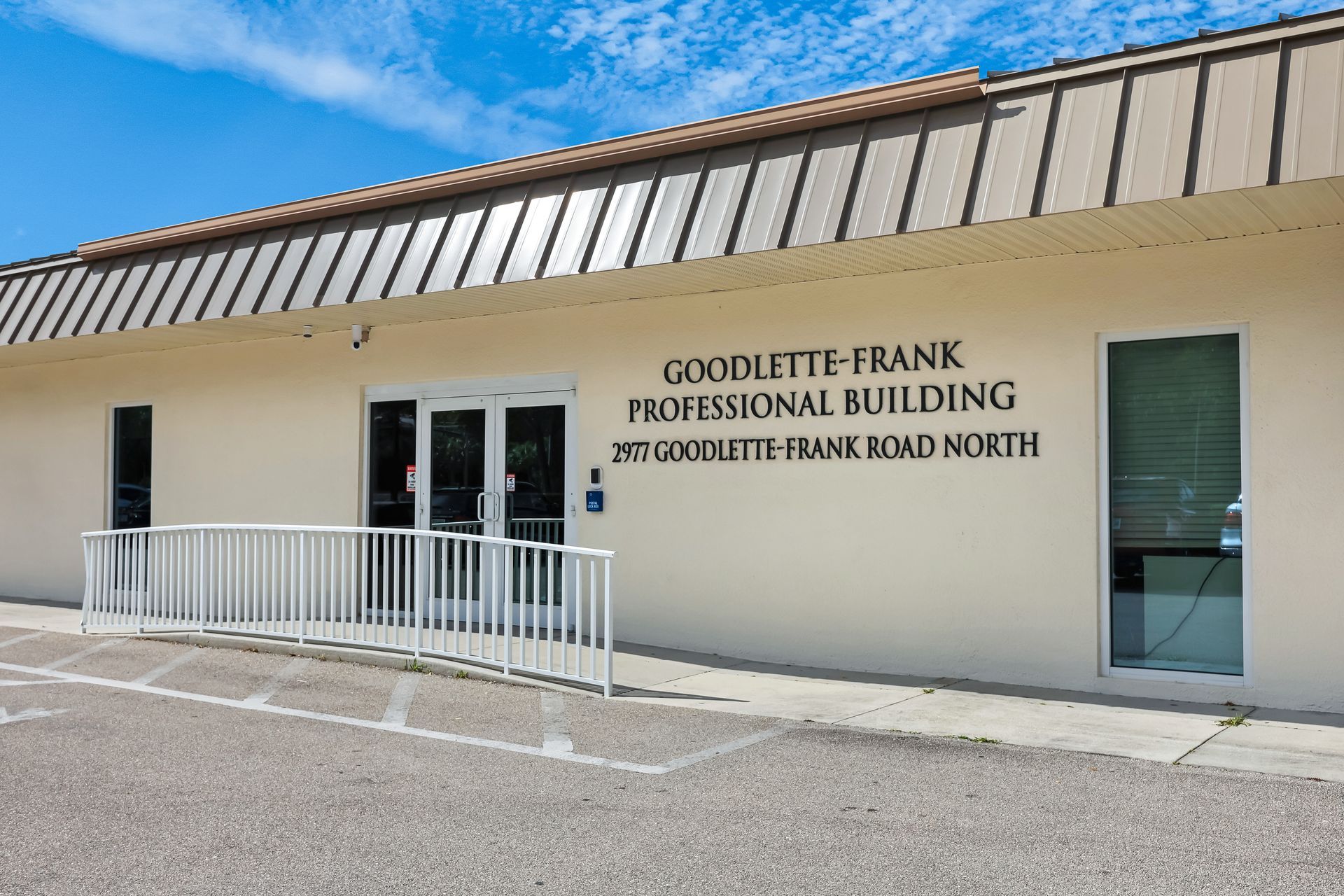 Goodlette-Frank Professional Building entrance with a ramp, white building, clear sky.