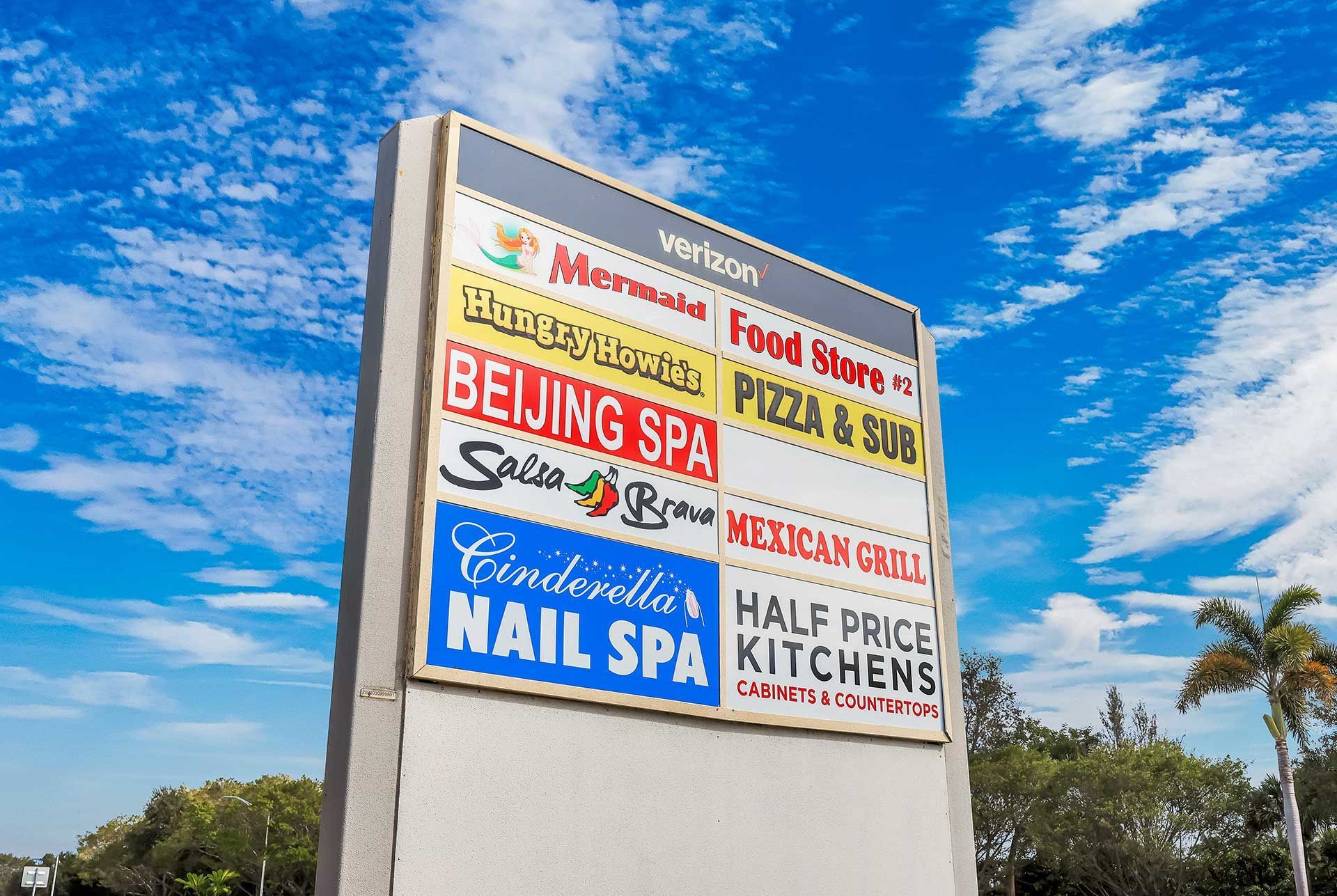 Sign for a shopping center with names of businesses.